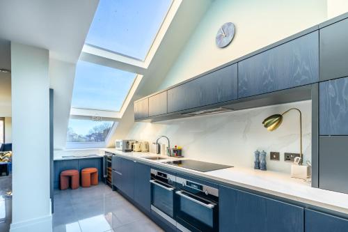 a kitchen with blue cabinets and a large window at Boutique Apartment at The Old Fire Station in York