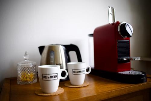 two coffee cups sitting on a table next to a coffee maker at Klein Soestdijk in Veenhuizen