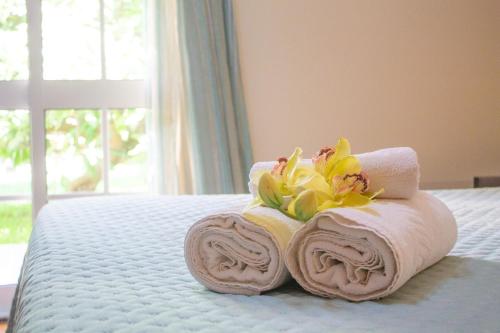 a pile of towels and flowers on a bed at Villa Atlântico, your family&friends retreat in Ponta do Sol