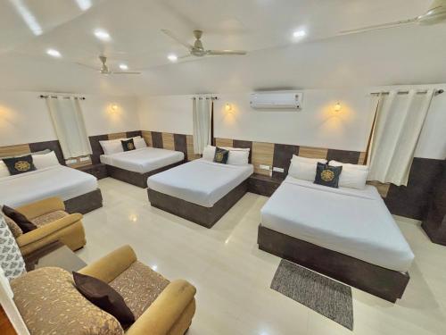 a hotel room with two beds and a couch at Riyavar Luxury Stay in Siddapur