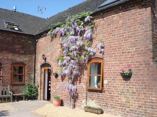 a brick building with purple flowers on the side of it at Highfields Farm B&B in Stone