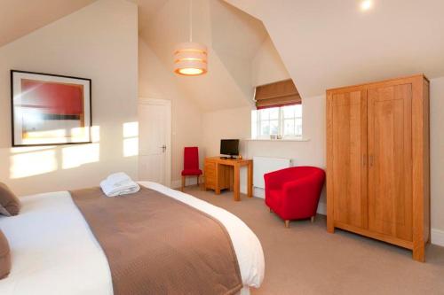 um quarto com uma cama e uma secretária com uma cadeira vermelha em Dbs Serviced Apartments em Castle Donington