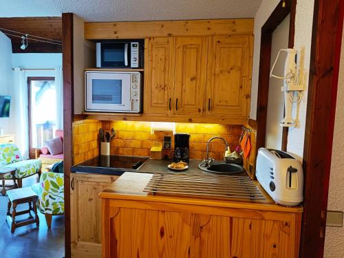 une cuisine avec un évier et un micro-ondes dans l'établissement Le Tavaillon, à Saint-Gervais-les-Bains
