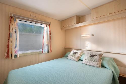 a small bedroom with a bed and a window at Mobile Home Manoli in Chiclana de la Frontera
