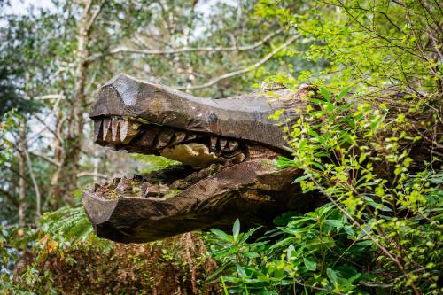 a statue of a dinosaur in the woods at Kells Bay House and Gardens in Kells
