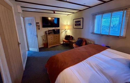 a bedroom with a large bed and a television at Lochindaal Hotel in Port Charlotte
