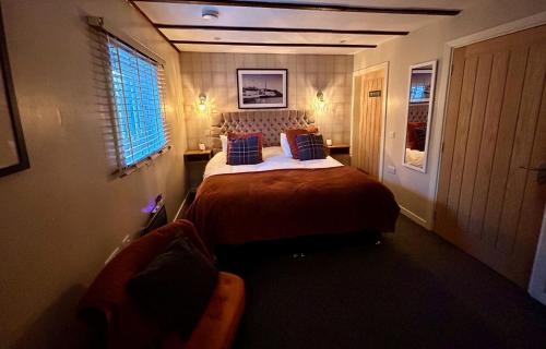 a bedroom with a bed and a chair in it at Lochindaal Hotel in Port Charlotte