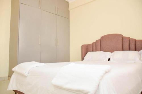 una habitación con una cama grande con sábanas y almohadas blancas en Croft Home, en Eldoret