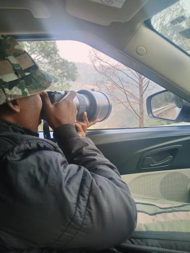 a man with a camera in a car looking through the window at Kingsman in Katra
