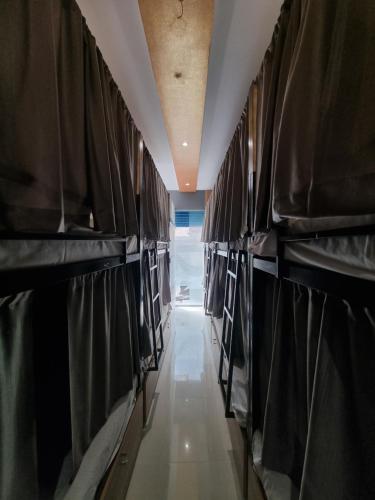a row of beds in a room with a hallway at The Plaza Dormitory in Mumbai