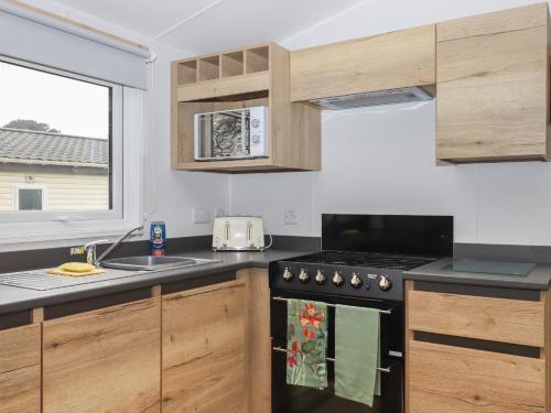 a kitchen with a stove and a sink and a window at 5 Manor Park in Bideford