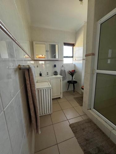 Un baño con ducha a ras de suelo y lavabo. en Gordon's Bay Townhouse, en Gordonʼs Bay