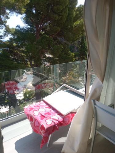 a table and chair on a balcony with a window at ToviMar Apartments in Taormina