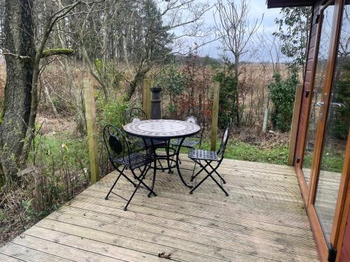 a table and chairs sitting on a wooden deck at Lilac Lodge Retreat - set in its own acre of land in Otley