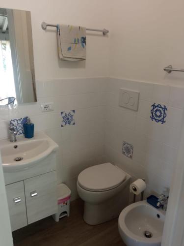 a white bathroom with a toilet and a sink at ToviMar Apartments in Taormina