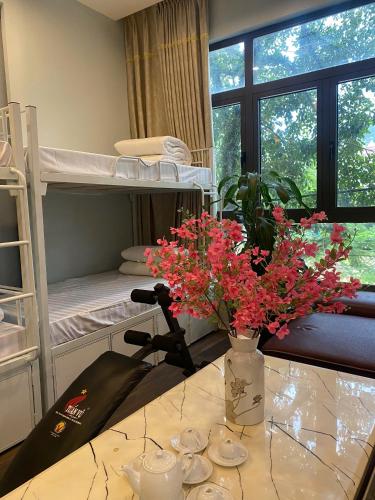 a room with bunk beds and a table with flowers at Mây Homestay in Cao Bằng in Cao Bằng