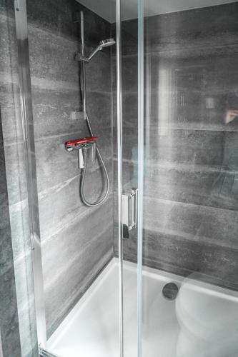 a shower with a glass door next to a toilet at The Grey Pearl Houseboat in Zwartsluis