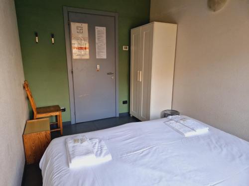 a bedroom with a white bed with a chair and a door at B&B e Ostello, Parco di Monza, CASCINA COSTA ALTA in Monza