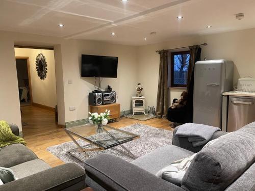 ein Wohnzimmer mit Couch und Fernseher in der Unterkunft Meagill Cottage Sleeps 4 with Hot Tub & Parking in Otley