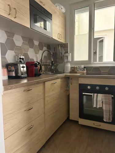 La cuisine est équipée d'armoires en bois et d'un four noir. dans l'établissement Cozy Appartment in Voltaire, à Paris