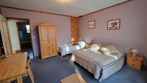 a bedroom with two beds and a wooden cabinet at Le Vieux Tilleul in Seyne