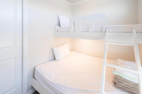a small bedroom with a white bed and shelves at Chincoteague Bay RV Resort & Cottages in Chincoteague
