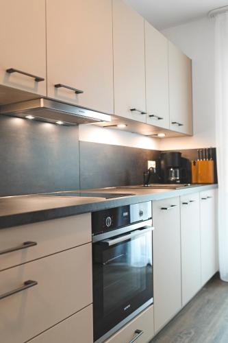 a kitchen with white cabinets and a black oven at Hotel & Appartements Nice Garni in Ichenhausen