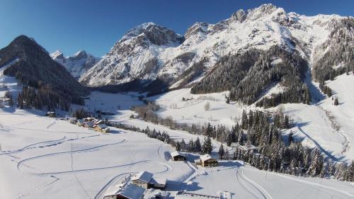 a snow covered mountain with a village in the foreground at Berghotel Lämmerhof in Sankt Martin am Tennengebirge