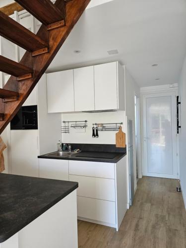 une cuisine avec des armoires blanches et des comptoirs noirs dans l'établissement Le fronton, à Saint-Jean-de-Luz