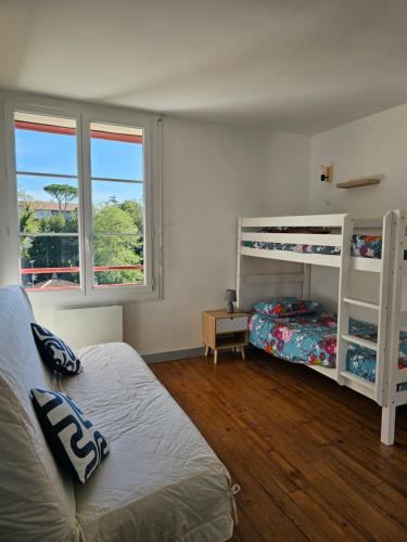 une chambre avec deux lits superposés et une fenêtre dans l'établissement Le fronton, à Saint-Jean-de-Luz
