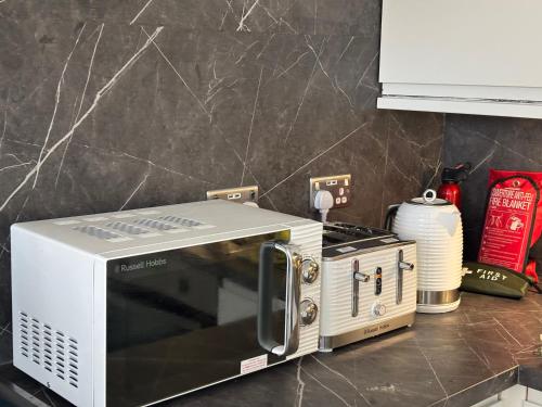 a microwave oven sitting on a counter in a kitchen at No 10, Ayr, 130m2, New Decor December 2024, All new entire 3 bedroom garden house in Ayr