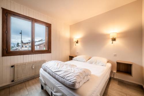 - une chambre avec un lit et une fenêtre avec une croix sur le mur dans l'établissement CHEVRULS A5: Appartement central avec deux chambres, à Morzine