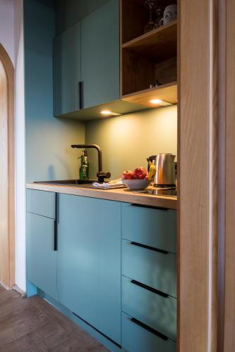 a kitchen with blue cabinets and a bowl of fruit on the counter at Das Nordberg Guesthouse in Garmisch-Partenkirchen
