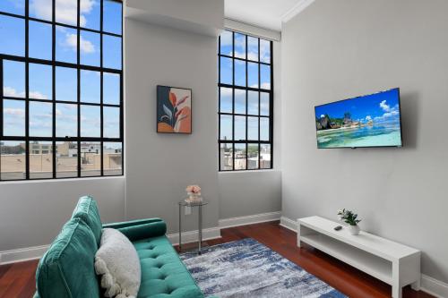 a living room with a green couch and windows at Modern NoLibs Studio - Pool & Gym in Philadelphia