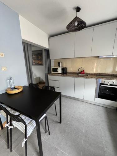a kitchen with a black table and white cabinets at Porto Smart Apartments- airport in Perafita