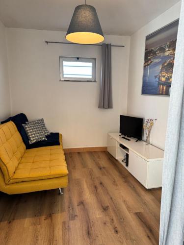 a living room with a yellow couch and a television at Porto Smart Apartments- airport in Perafita