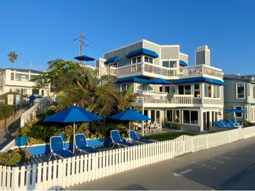 a large house with blue chairs and umbrellas at 90210 Beach House Middle Unit in Hermosa Beach