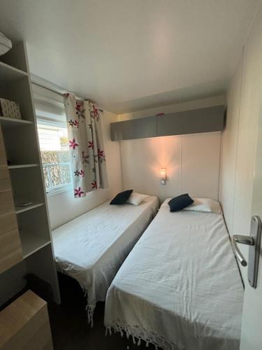 deux lits dans une petite pièce avec une fenêtre dans l'établissement Mobil home dans Parc Résidentiel de Loisirs, à Hauteville-sur-Mer