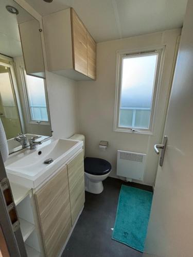 une salle de bain avec un lavabo et des toilettes et une fenêtre dans l'établissement Mobil home dans Parc Résidentiel de Loisirs, à Hauteville-sur-Mer