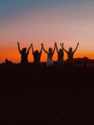 a group of people with their hands in the air at sunset at The Hideaway Retreat in Omagh