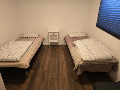 two beds in a room with a wooden floor at Beautiful 2 rooms apartment in kløfta,near oslo airport& oslo in Klofta