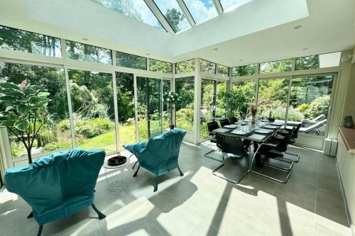 une véranda avec une table, des chaises et des fenêtres en verre dans l'établissement Villa de standing - Pleine nature - Jacuzzi, à Guidel