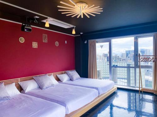 two beds in a room with a red wall at AnsouHouseメゾネット 大阪ドーム in Osaka