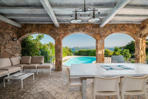 a patio with a table and chairs and a pool at Villa Mimosa in Golfo Aranci