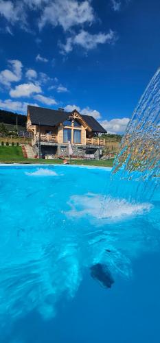 a fountain in the water in front of a house at Jaworki Prestige SPA in Jaworki