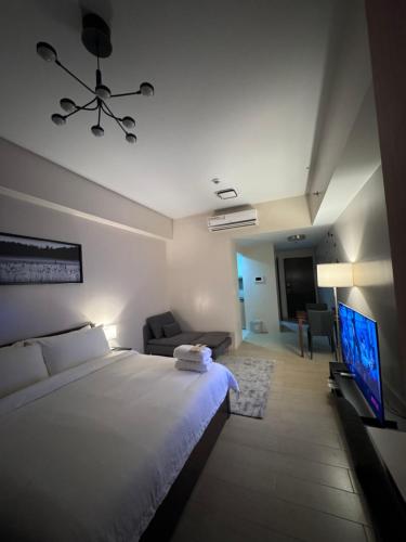 Un dormitorio con una cama, un sofá y un televisor. en 81 Newport Blvd Cluster 4 Unit 10C by Rechelle Nunag, en Manila