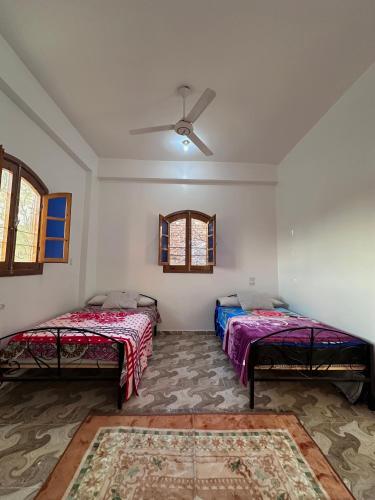 Cette chambre comprend deux lits et un ventilateur de plafond. dans l'établissement Ashry, à Al Aqālitah