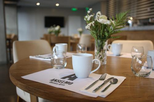 a wooden table with a coffee cup and silverware on it at Anselmo Buenos Aires, Curio Collection by Hilton in Buenos Aires