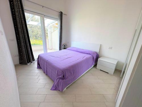 Un dormitorio con una cama morada y una gran ventana. en Affittimoderni Viddalba Bouganville VIBO09, en Viddalba