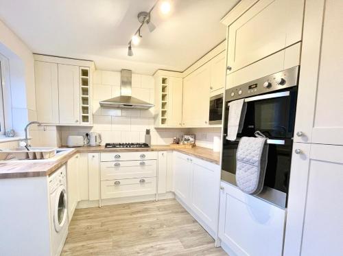 a white kitchen with white cabinets and a sink at Large home near shops and resturants in lovely area wt parking in Kent